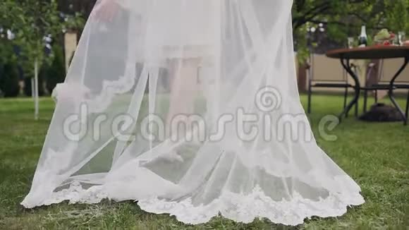 年轻新娘穿着长长的花边白色婚纱和戴着婚纱的婚纱穿着他的婚纱视频的预览图
