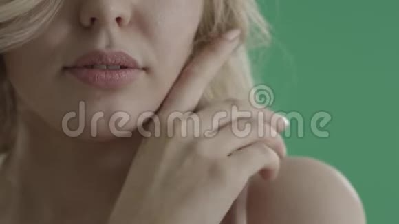 性感的金发女人在绿色屏幕上抚摸她的嘴唇脖子和肩膀视频的预览图