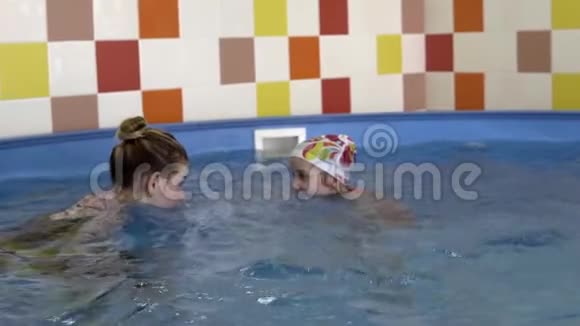 小女孩和泳池里的教练互相看着视频的预览图