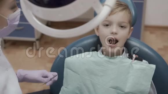 牙医用角探针和镜子检查小男孩的牙齿视频的预览图