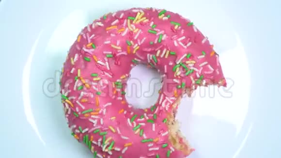 有人咬了一个釉面甜甜圈在白色的盘子上快速旋转视频的预览图