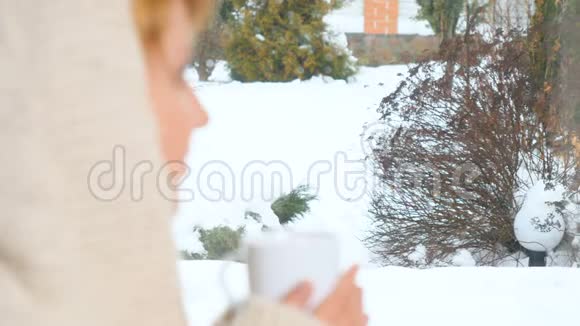 戴帽子的女孩在窗边喝茶享受冬天视频的预览图