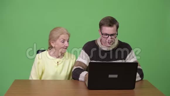 快乐的高级女商人和年轻的帅哥一起使用笔记本电脑视频的预览图