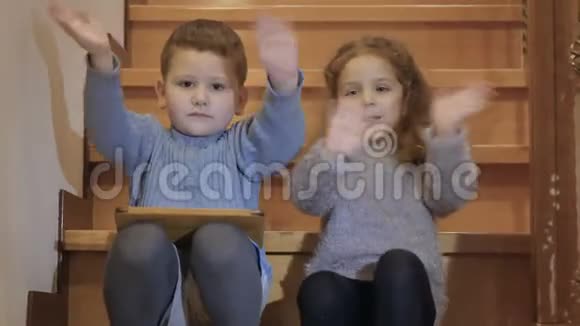 小孩子坐在楼梯上挥手竖起大拇指视频的预览图