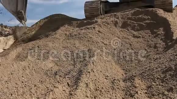 挖掘机正在准备一堆沙子以便在建筑工地的卡车上装载视频的预览图