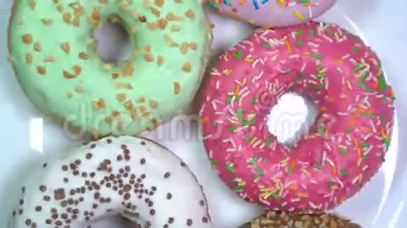 许多明亮和五颜六色的甜甜圈宏观射击快速旋转在一个旋转的盘子视频的预览图