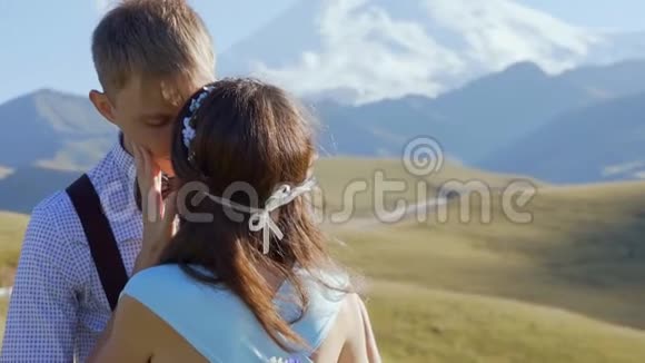 一对时尚的年轻夫妇在阳光明媚的日子里在群山的背景下视频的预览图