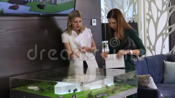 两个商业女孩在看一栋商业大楼的模型视频的预览图