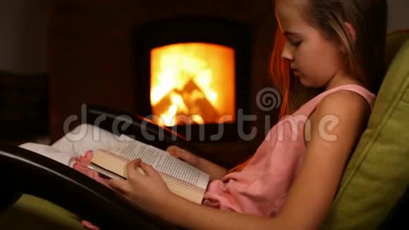 小女孩坐在火炉旁的摇椅上看书视频的预览图