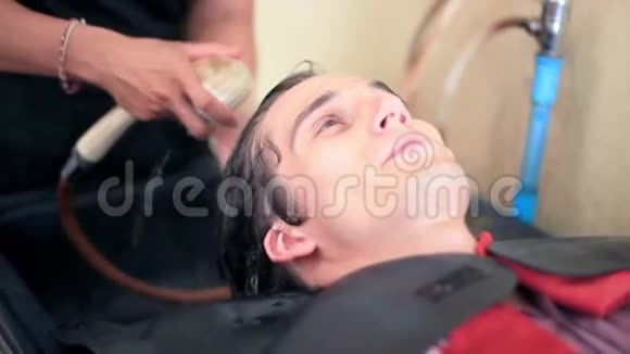 理发师在男沙龙给年轻帅哥洗头理发店沙龙的客户1920x1080个视频的预览图
