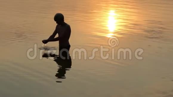 在斯洛莫的日落时分一个少年在湖中举起一把水视频的预览图