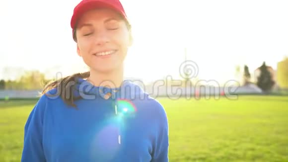 日落时体育场里一个爱运动的微笑女孩的肖像视频的预览图