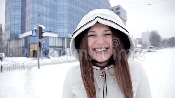一个年轻的女孩在寒冷的冬天为相机摆姿势寒冷的雪视频的预览图