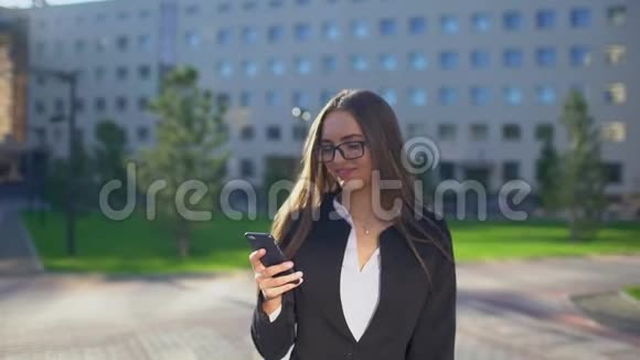 美丽的年轻女商人或穿着白色衬衫的学生在城市里使用现代智能手机专业人士视频的预览图
