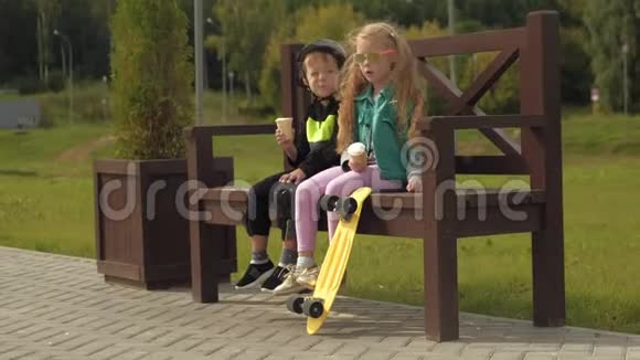 一个男孩和一个女孩坐在公园的长凳上吃冰淇淋夏季视频的预览图