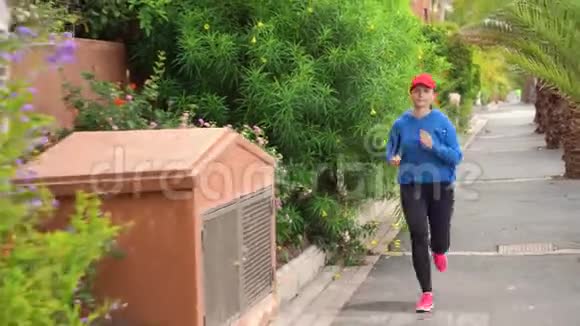 女人沿着街道在热带小巷里慢跑视频的预览图
