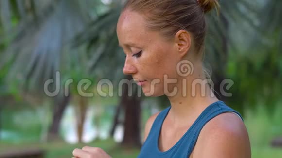 在热带公园做运动后年轻女子从塑料瓶里喝水视频的预览图