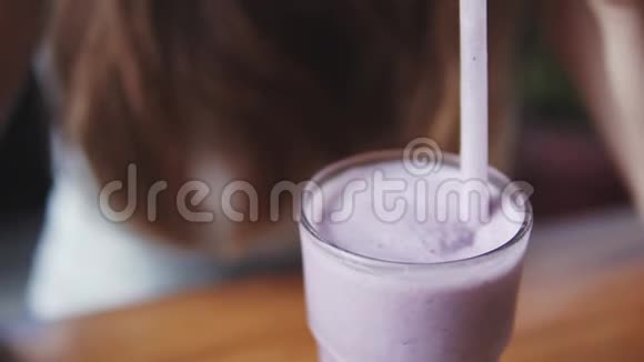 年轻漂亮的欧洲女孩在炎热的夏日在咖啡馆里和蓝莓混合喝冷牛奶鸡尾酒关门视频的预览图
