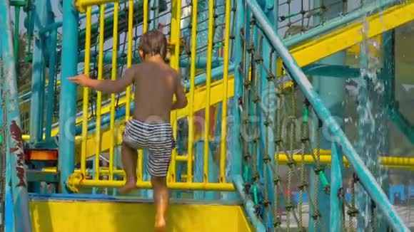 一个小男孩从楼梯上爬升到水中的一个高水位滑水开始的最高镜头视频的预览图