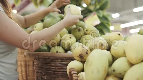 女人在超市挑选绿色芒果一个从杂货店拿芒果的女人女孩选择视频的预览图