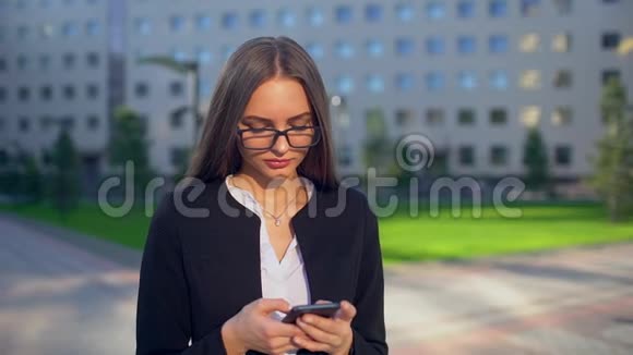 美丽的年轻女商人或穿着白色衬衫的学生在城市里使用现代智能手机专业人士视频的预览图