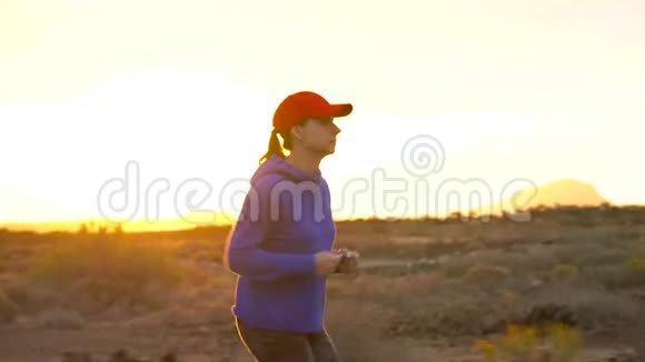 日落时女人沿着荒无人烟的地方奔跑背景上的山脉视频的预览图