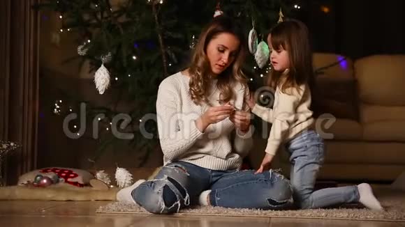 妈妈和女孩正在看圣诞树下的圣诞树视频的预览图