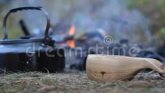 把茶从茶壶里倒入火旁边的木杯里视频的预览图
