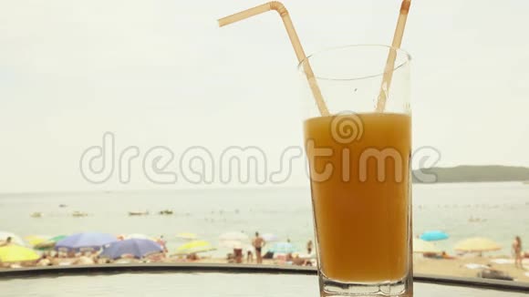 在模糊的海滩上喝一杯新鲜橙汁视频的预览图