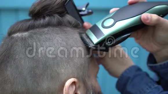 漂亮的女理发师用电动剃须刀和梳子剪客户的头发视频的预览图