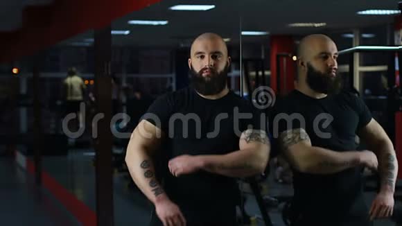自信的肌肉男看着相机人们在健身房锻炼镜子视频的预览图