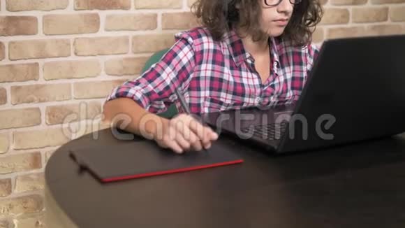 差不多了一个少年头发卷曲黑发穿着格子衬衫使用手写笔在一个图形平板上工作视频的预览图