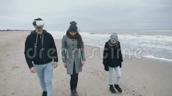 21世纪的一家人沿着海滩散步戴着VR眼镜的父亲视频的预览图