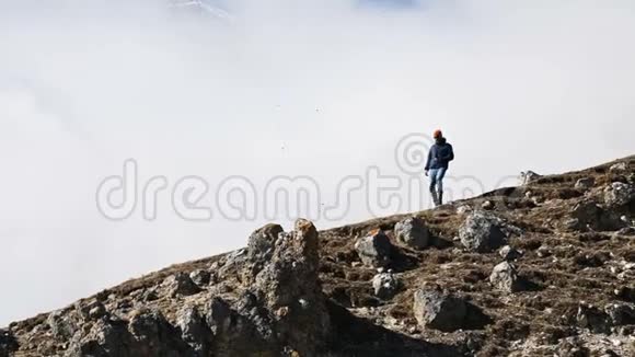 戴着帽子太阳镜脖子上戴着相机的胡子男摄影师爬上了山坡视频的预览图