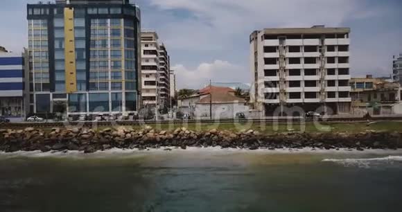 无人驾驶飞机沿着斯里兰卡科伦坡的海岸街道飞行交通车辆和建筑物的空中跟踪拍摄视频的预览图