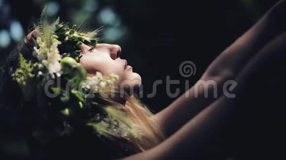 树林中神秘女孩的肖像举行仪式她穿着连衣裙头上戴着花环开关视频的预览图