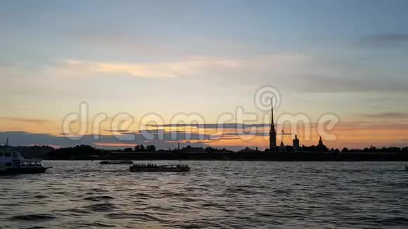 圣彼得堡中心河上有帆船在夕阳下彼得和保罗堡的轮廓视频的预览图