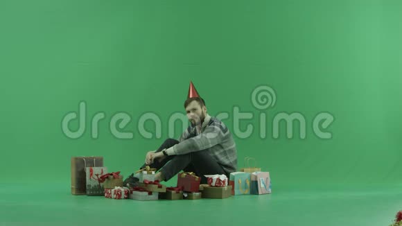 年轻的胡须男在地板上打开生日礼物绿色的关键背景视频的预览图