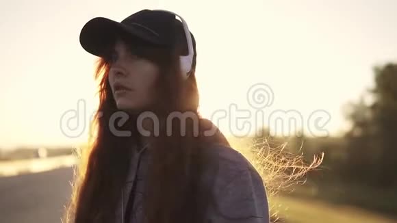 一个穿洞的红发女孩的特写肖像听着耳机里音乐的年轻女子在光线下视频的预览图