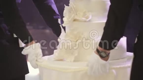 服务员拿着结婚蛋糕新娘和新郎切婚礼蛋糕特写镜头视频的预览图