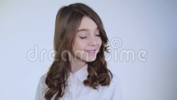 年轻漂亮谦虚的女孩在镜头前摆弄她的头发和微笑视频的预览图