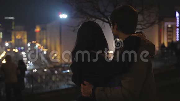 爱的年轻男女轻轻拥抱看着浪漫的夜城灯视频的预览图