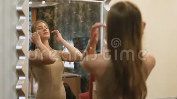 穿着一件优雅棕色连衣裙的女人站在镜子前微笑着视频的预览图