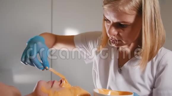 美容店的美容师用水果面膜覆盖客户的整个面部视频的预览图