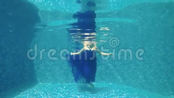穿着蓝色裙子的漂亮女孩在游泳池里水中冥想视频的预览图