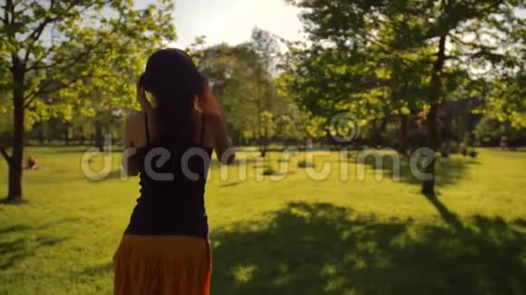 美丽的红头发女性长发在公园里享受音乐视频的预览图
