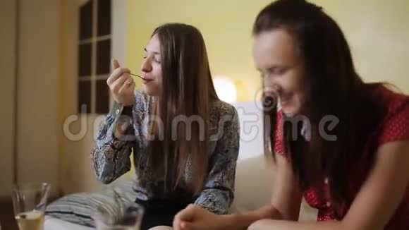 两个女人在家里的沙发上聊天喝酒吃蛋糕视频的预览图