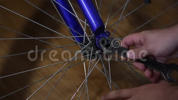 那个人把自行车上的轮子摘下来从轮轴上拧下螺母视频的预览图