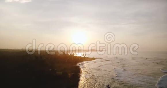 无人机在史诗般的夕阳反射下在白色的海浪中向后飞行到达令人惊叹的热带天堂海岸线视频的预览图