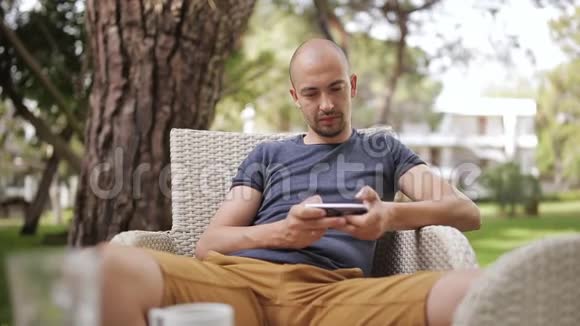 严肃的男人在家门口玩智能手机视频的预览图
